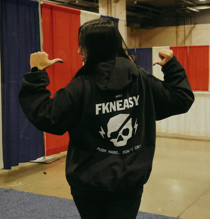 Person wearing a black hoodie with 'FKNEASY' branding in an indoor setting.