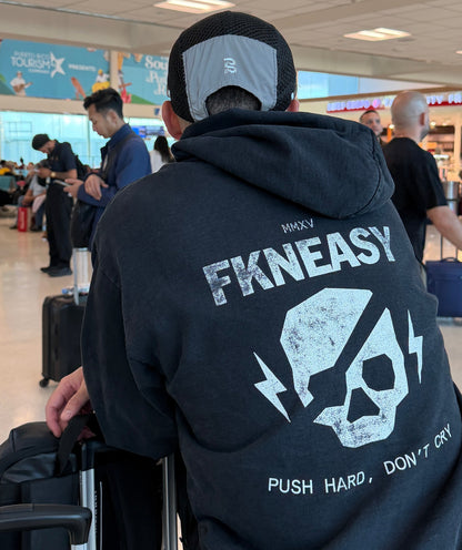 Person wearing a black hoodie with 'FKNEASY' branding in an airport setting